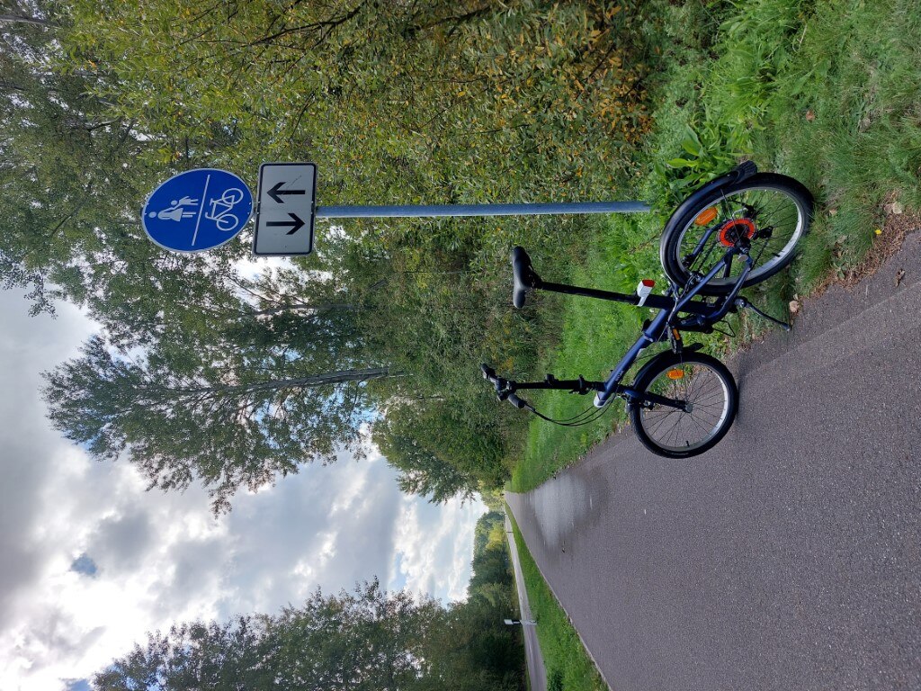 Fahrrad-/Fußweg mit Dienst-Faltradrad am Verkehrsschild