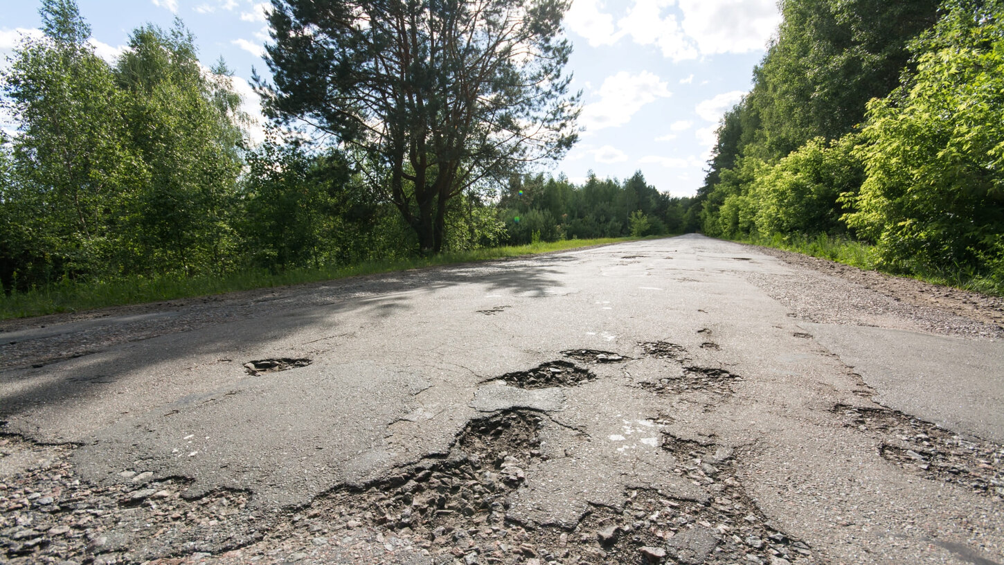 Straße im schlechten Zustand mit vielen Schlaglöchern