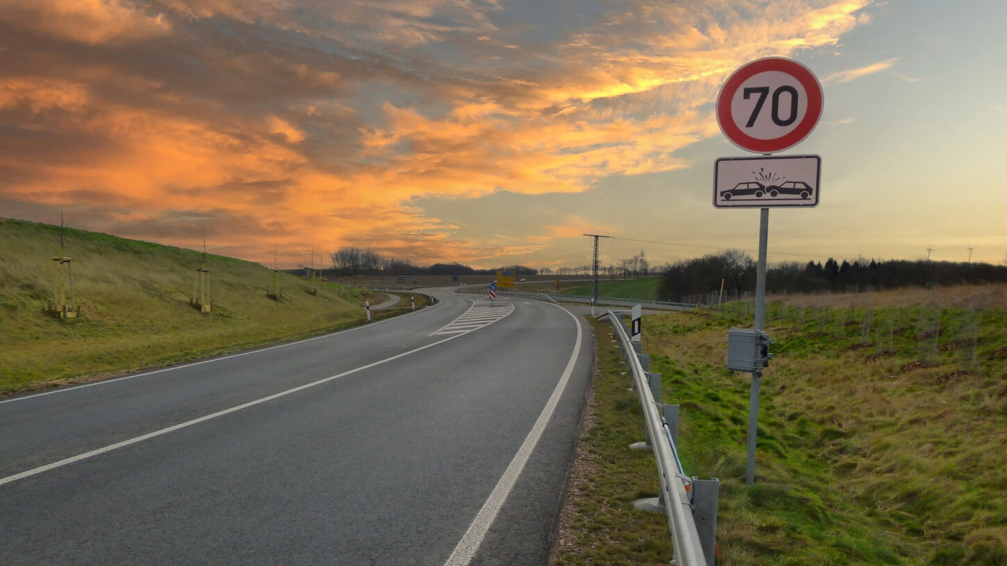 Verkehrsschild Tempo 70, Unfallschwerpunkt an Landstraße bei Abenddämmerung